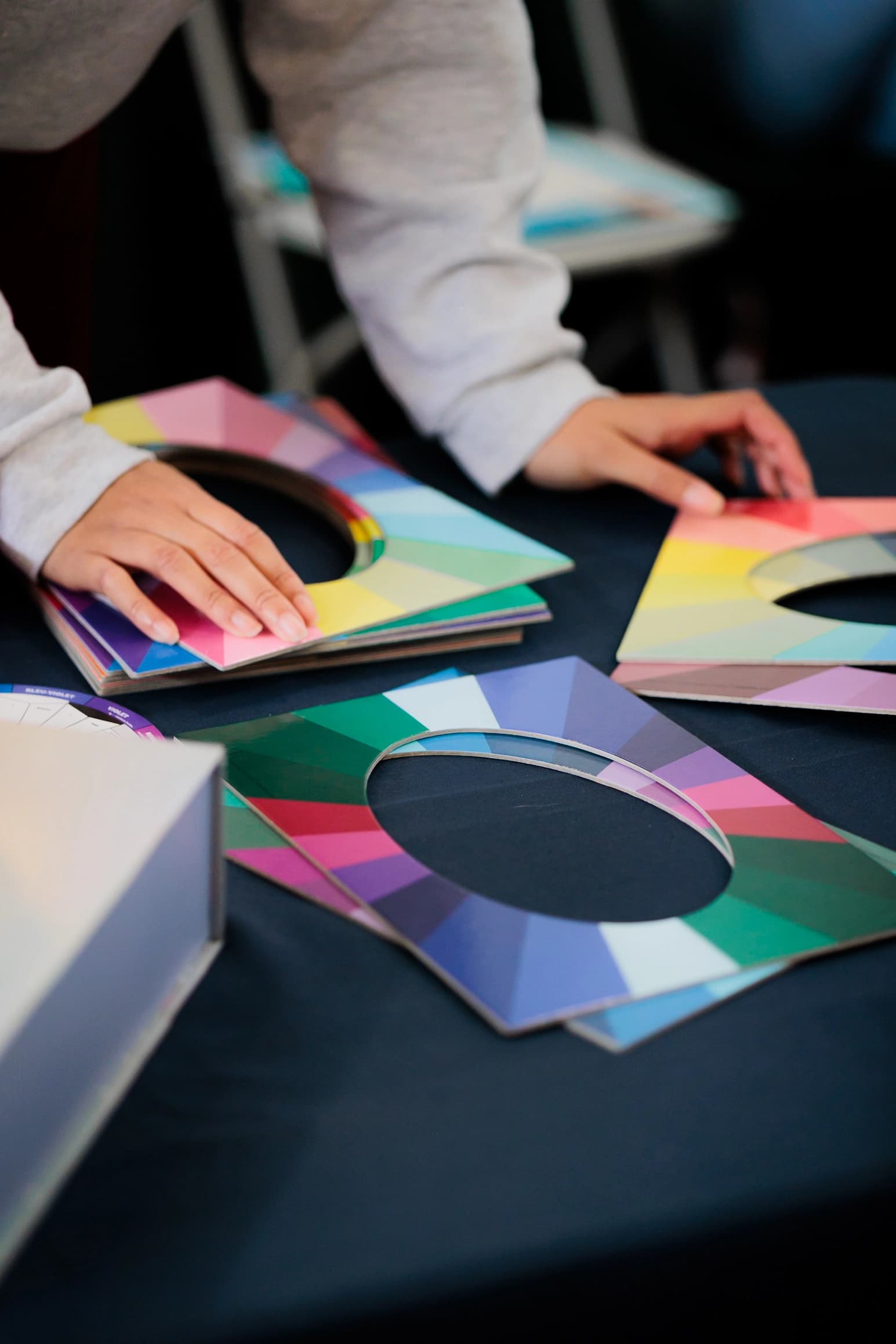 Détail des mains disposant des nuanciers colorés pendant un atelier colorimétrie
